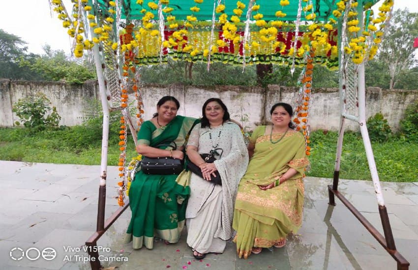 sixteen-women-adorned-with-environment-on-greenery-teej