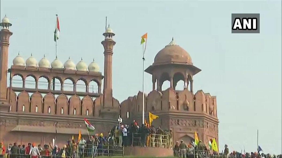 A protestor hoists a flag from the ramparts of the Red Fort in Delhi