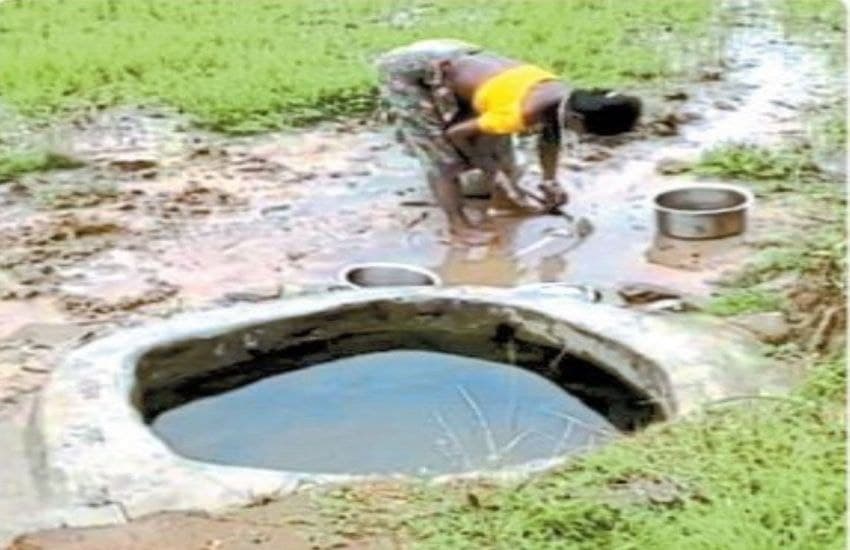 बैलाडीला इलाके में गड्ढे से पानी भरती आदिवासी महिला 