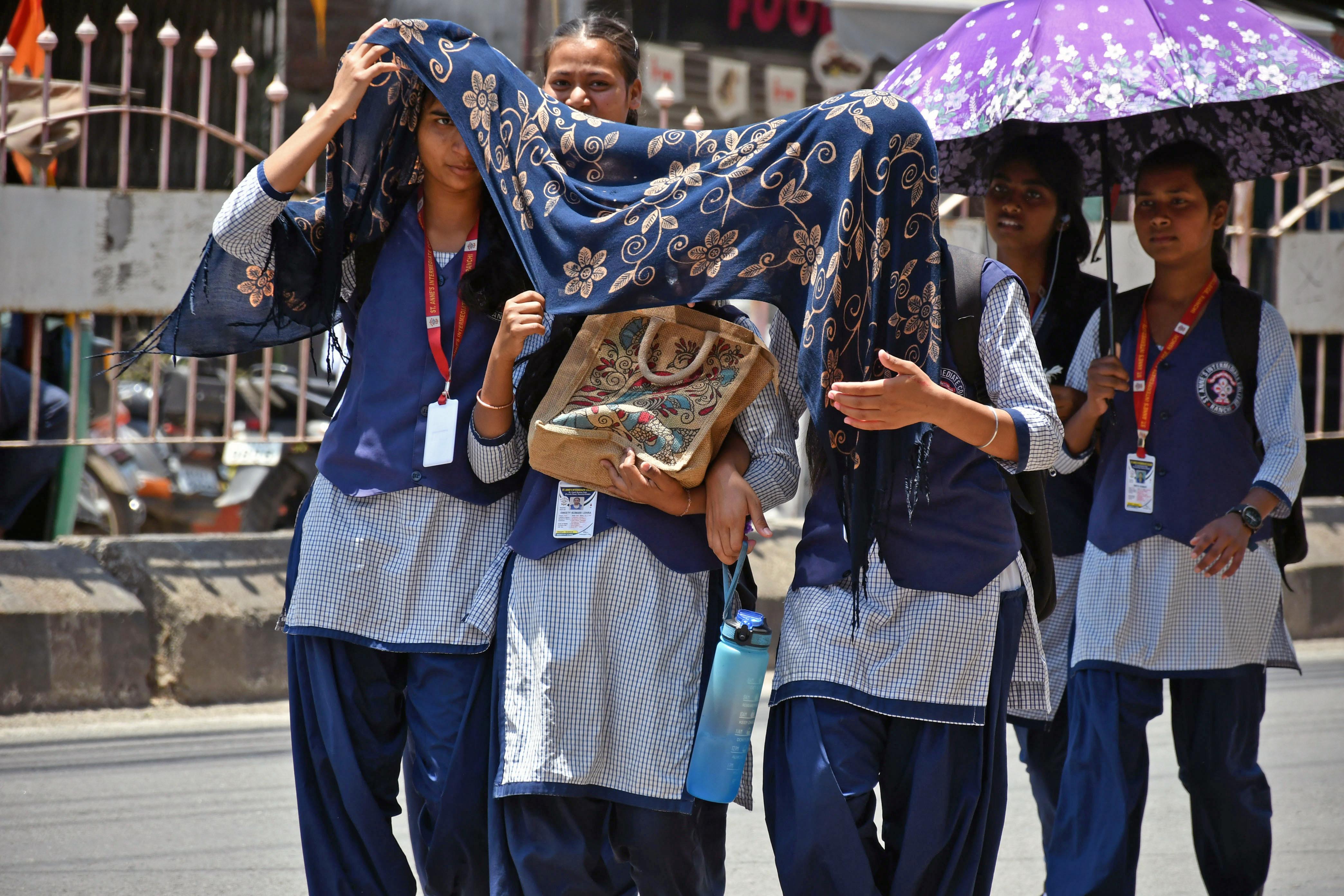Students use umbrellas to protect themselves from the heat