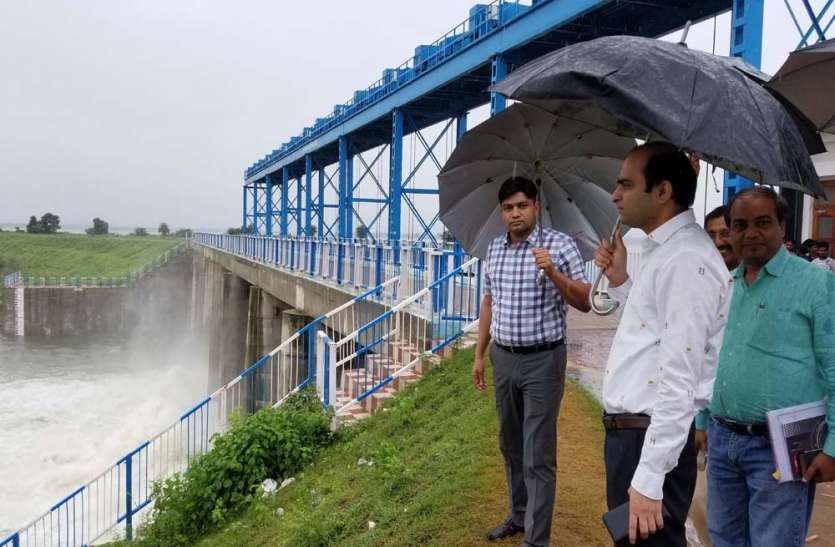 inspection of dams by dm jhansi and announce 2 day holiday in schools भारी बारिश की चेतावनी के बीच छतरी लेकर बांध देखने निकले ये साहब, स्कूलों में छुट्टी