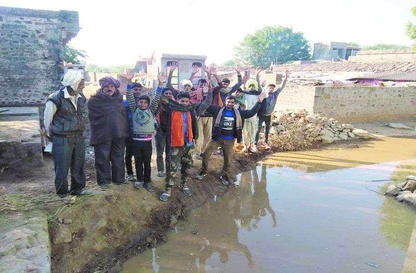 मिट्टी के अवरोधक पर विरोध जताते ग्रामीण एवं भरा पानी लोगों ने रोका गंदा पानी