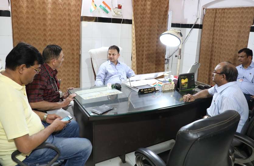 चर्चा करते कलेक्टर और मोबाइल में व्यस्त अधिकारी