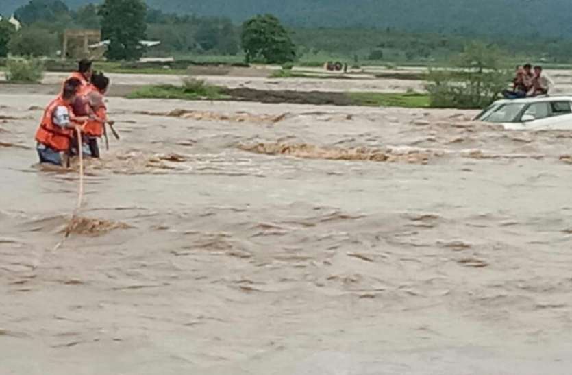 home guard rescued तेज बहाव में बही जा रही थी कार, पत्थर में फंसते ही कार की छत में चढ़कर युवकों ने बचाई जान, देखें वीडियो
