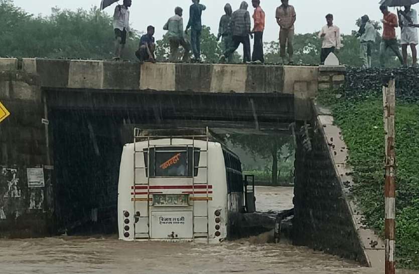 patrika अंडरब्रिज के पानी में फंसी बस, काच फोड़कर यात्रियों को निकाला को लोगों ने बचाया