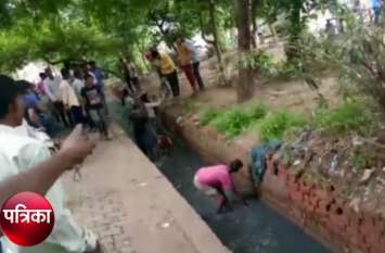 people see currency in drain and jumped in ghaziabad video viral नाले में अचानक बहते दिखे नोट तो राहगीरों ने बच्चों समेत लगा दी छलांग, बीन ने लगे रुपये और फिर - देखें वीडियो