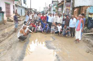 Road ravaged by rain, then demonstrated in mud बारिश में खस्ताहाल हुई सड़क, तो कीचड़ में बैठकर किया प्रदर्शन