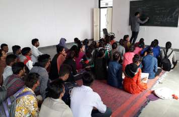 College students are sitting on the floor फर्श पर बैठ कर पढ़ रहे हैं कॉलेज के छात्र
