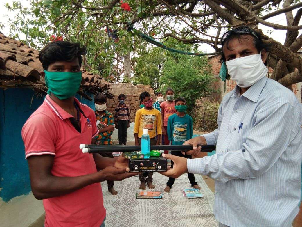 teacher Dinesh giving radio to children and teaching.jpg