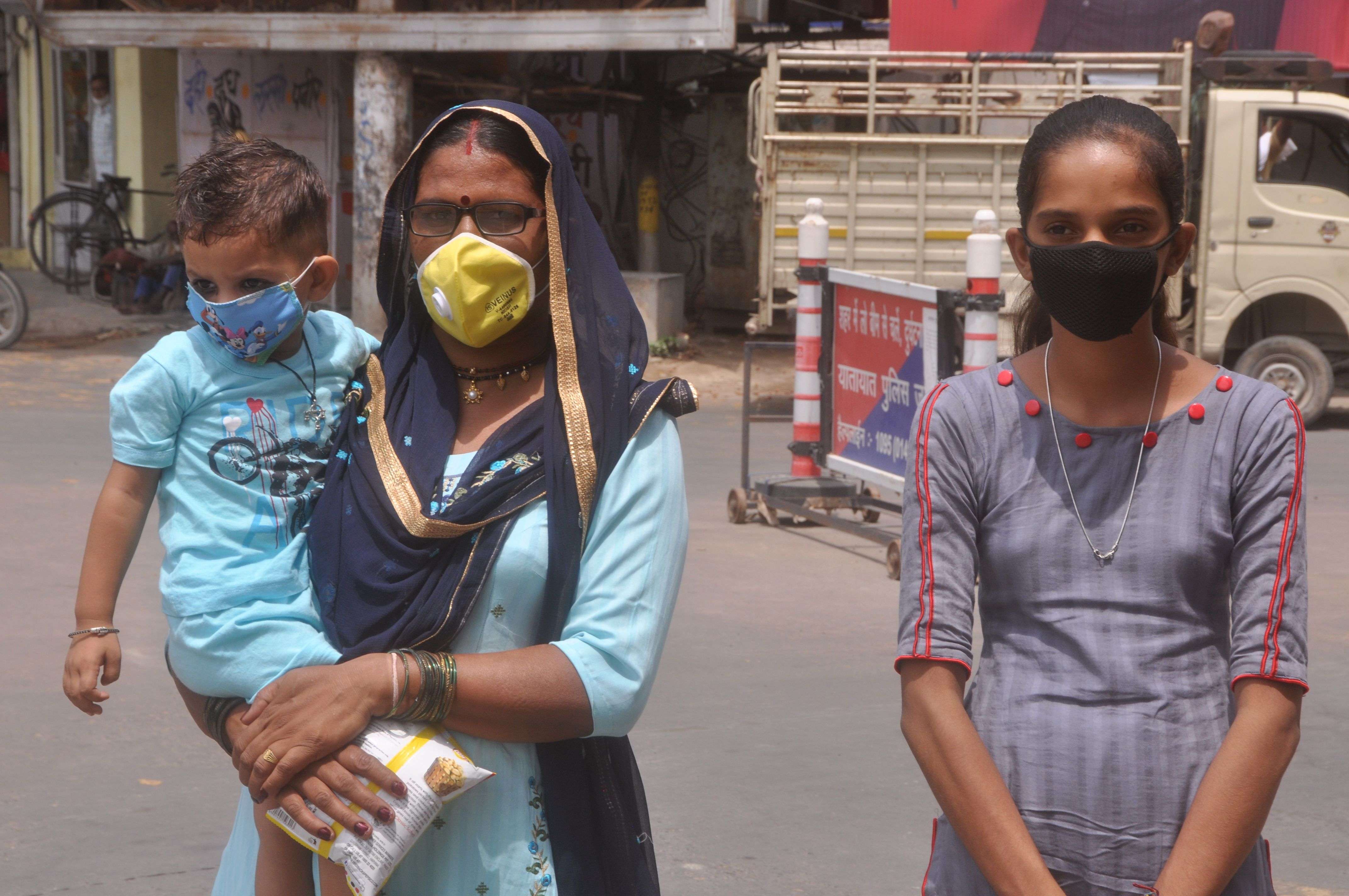 मुंह पर मास्क लगाए बच्चे को गोद में उठाए रविन्द्र पथ से गुजरती महिला व युवती