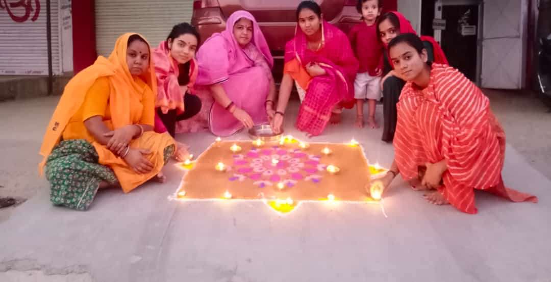 घरों में दीपक जलाती महिलाएं।