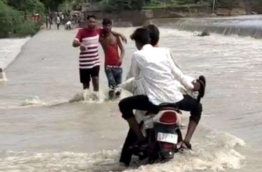 जान जोखिम में डालकर बहते पानी को पार कर रहे लोग जान जोखिम में डालकर बहते पानी को पार कर रहे लोग