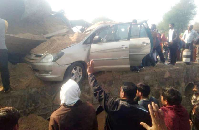 बजरी से भरी ट्रॉली के नीचे दबी कार, एक जना घायल बजरी से भरी ट्रॉली के नीचे दबी कार, एक जना घायल