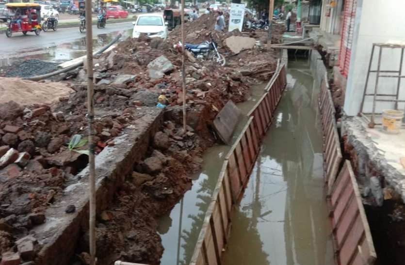 बारिश में बन रही नाली, सड़क पर फैली निर्माण सामग्री बारिश में बन रही नाली, सड़क पर फैली निर्माण सामग्री