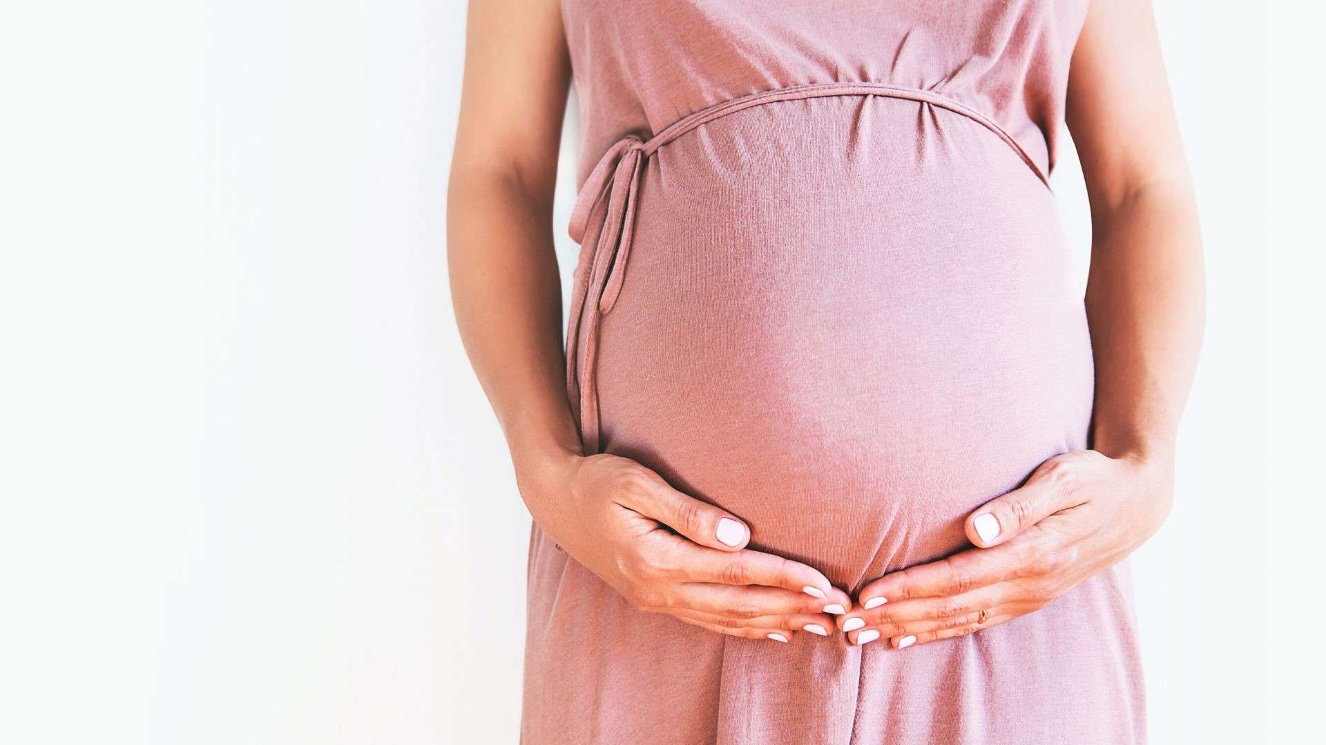 pregnant-woman-wearing-pink-holding-her-belly.jpg