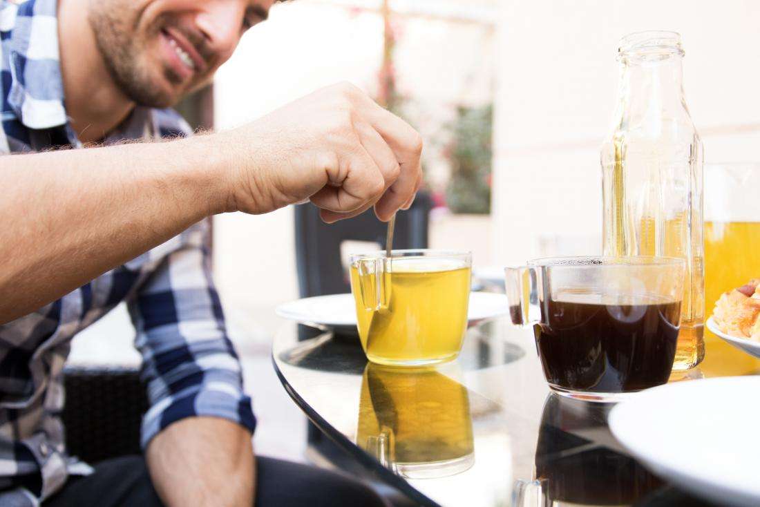 men-stirring-green-tea-in-clear-mug-next-to-different-cups-of-tea.jpg