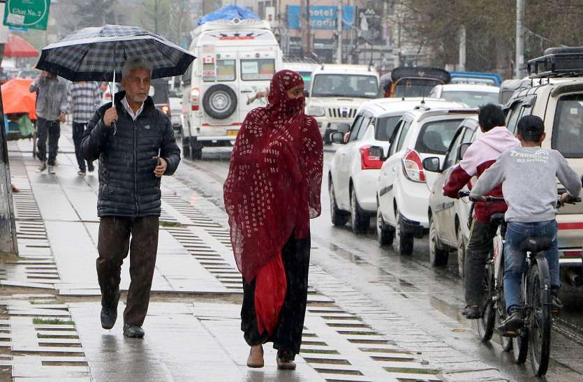 श्रीनगर में गुरुवार को बारिश के बीच पैदल चलते लोग।